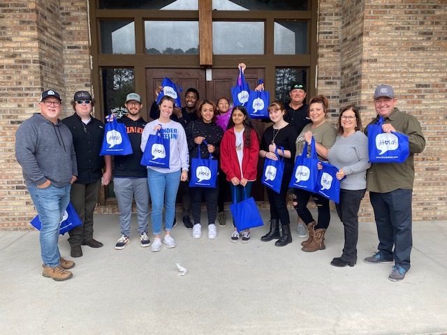 Diverse people happily taking a picture while holding a blue bag